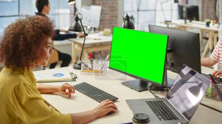Vista de ángulo alto de una trabajadora que usa la computadora en una oficina moderna y brillante. Administrador Sonriendo y Preparando una Presentación Usando Pantalla Verde