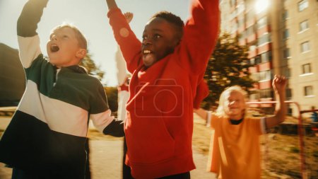 Young Black Boy beim Fußballspielen mit verschiedenen Freunden. Multiethnische Kinder beim Fußballspielen in der Nachbarschaft. Spieler feiern das Tor
