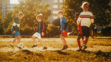 Téléchargez les photos : Amis du quartier jouant au football à l'extérieur dans la cour arrière urbaine. Les enfants multiculturels jouent au football ensemble dans les banlieues. Bonne Enfance et Sport - en image libre de droit