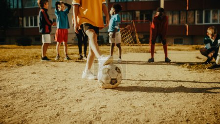 Téléchargez les photos : Fille mignonne jouant Keepie Uppies avec un ballon de football avec des enfants multiethniques dans le quartier. heureux les garçons et les filles jongler l 'ballon dans l' - en image libre de droit