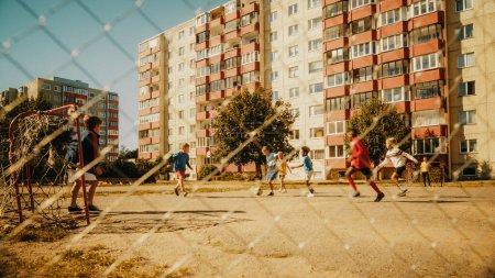 Sportliche multiethnische Kinder, die an einem sonnigen Sommertag in ihrem Hinterhof Fußball spielen. Fröhliche Jungen und Mädchen genießen ein Fußballspiel
