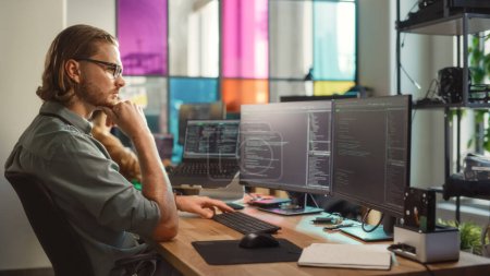 Scientifique professionnel des données masculines écrivant le code sur l'ordinateur de bureau dans l'espace de bureau élégant de coworking. Homme caucasien utilisant un logiciel pour analyser