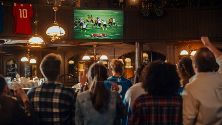 Gruppe von American-Football-Fans, die eine Live-Übertragung eines Spiels in einem Sport-Pub im Fernsehen verfolgen. Menschen jubeln, unterstützen ihr Team. Menschenmenge wird ekstatisch