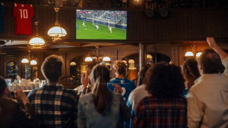 Eine Gruppe von Freunden schaut sich ein Live-Fußballspiel in einer Sportbar im Fernsehen an. Aufgeregte Fans jubeln und schreien. Junge Leute feiern, wenn ein Team ein Tor erzielt