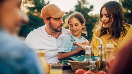 Portrait d'un beau jeune père tenant sa jolie petite fille sur le tour lors d'un dîner en plein air avec de la nourriture et des boissons. Famille heureuse Avoir une