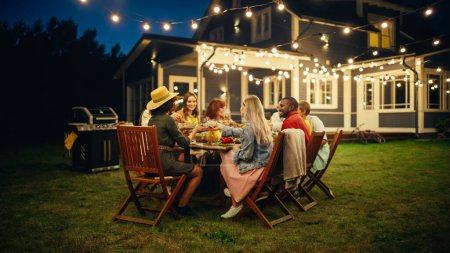 Photo for Family and Multicultural Friends Celebrating Outside at Home in the Evening. Group of Children, Adults and Old People Gathered at a Table, Having Fun - Royalty Free Image