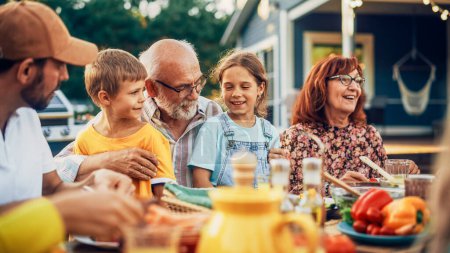 Portrait d'un grand-père aîné heureux tenant ses petits-enfants brillants et talentueux sur le tour lors d'un dîner en plein air avec de la nourriture et des boissons. Famille