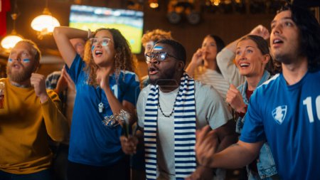 Diverse Soccer Fans Watching a Live Football Match Broadcast in a Sports Pub on TV. People Cheering, Supporting Their Team. Crowd Goes Ecstatic When