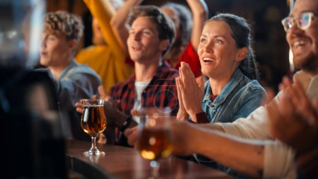 Portrait of a Beautiful Female Sitting at a Pub Counter with Group of Diverse Friends, Watching and Cheering for a Live Soccer Match. Supportive Fans