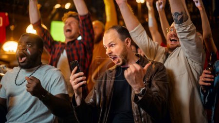 Portrait of a Emotional Young Man Holding a Smartphone, Happy About the Sports Bet on a Soccer Match. Looking Like an English Pub Regular, Wearing a