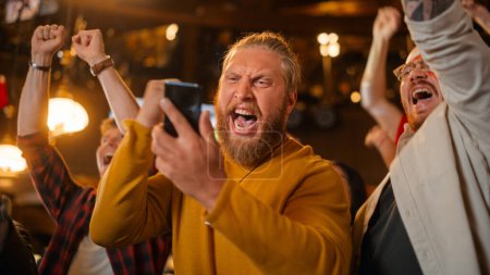 Excited Masculine Man Holding a Smartphone, Feeling Nervous About the Sports Bet He Put on a Favorite Soccer Team. Ecstatic When Football Team Scores