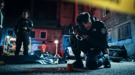 Asiatischer Polizist fotografiert markante Beweise, während Polizeichef und Detektivin im Hintergrund über die in Tüten verpackte Leiche der Opfer sprechen