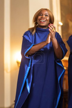 Retrato de la alegre mujer afroamericana vestida de azul en la iglesia dominical. Black Christian Cantante del Evangelio Femenino Cantando y aplaudiendo, Feliz de ser