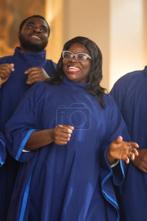 Téléchargez les photos : Chanteuse chrétienne noire de l'Évangile chantant, heureuse de répandre l'amour du Seigneur Jésus-Christ. gai afro-américain femme en robe bleue dans - en image libre de droit