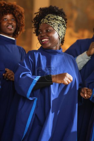 Téléchargez les photos : Chanteuse chrétienne noire de l'Évangile chantant, heureuse de répandre l'amour du Seigneur Jésus-Christ. gai afro-américain femme en robe bleue dans - en image libre de droit