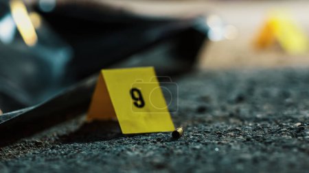 Plan rapproché extrême : Une balle trouvée près du cadavre de la victime suggère un pistolet comme arme à feu meurtrière. Tir de masse entraînant la mort tragique de beaucoup