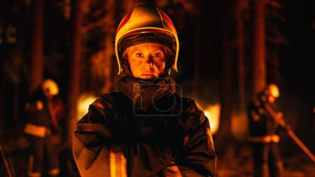 Portrait of a Brave Female Firefighter Standing in Professional Protective Uniform and Wearing a Helmet, Looking at Camera and Posing. Standing in a
