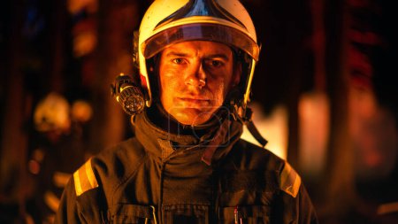 Portrait d'un brave jeune pompier adulte en uniforme de sécurité et d'un casque avec une lampe de poche. Pompier professionnel regardant la caméra