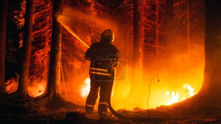 Elite Firefighter Methodically Extinguishing a Large Forest Fire with High-Pressure Water Running From Firehose. Firemen Brigade Rescuing Wildland
