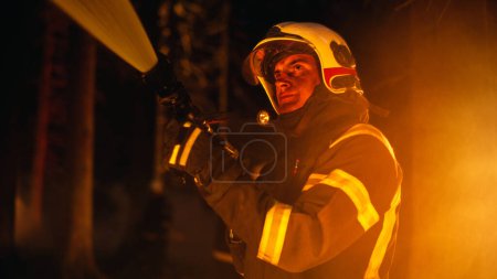 Erfahrener Feuerwehrmann löscht einen Wildlandbrand tief im Wald. Profi-Trupp in Schutzanzügen und Helmen mit Feuerwehrschlauch und Ausrüstung