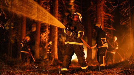 Erfahrener afroamerikanischer Feuerwehrmann löscht einen Wildlandbrand tief im Wald. Profi in Schutzuniform und Helm mit Feuerwehrschlauch