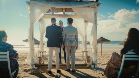 Handsome Gay Couple Walking Down the Aisle at Outdoors Wedding Ceremony Venue Near the Ocean. Two Happy Men in Love Share Their Big Day with Diverse