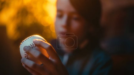 Fermer Portrait d'un jeune fan de sport tenant un ballon de baseball blanc à la maison. Un garçon excité regardant le ballon et le retournant. Profiter des loisirs