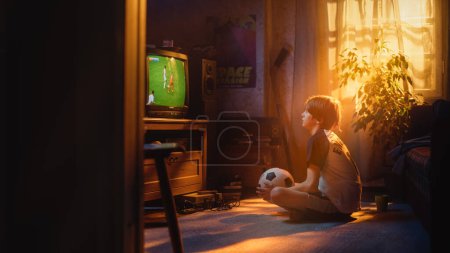 Jeune fan de sport regarde un match de football à la télévision à la maison. Garçon curieux soutenant son équipe de football préférée, se sentant fier quand les joueurs marquent un but