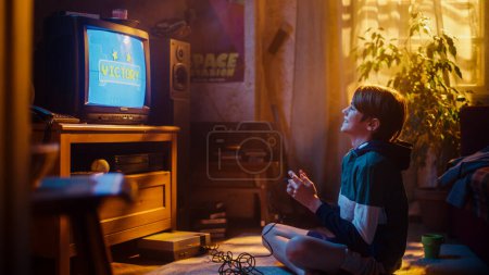 Young Boy spielt Achtziger Jahre 2D Arcade Weltraum-Shooter-Spiel auf einer Spielkonsole zu Hause in seinem Zimmer mit Old-School-Interieur. Kind gewinnt erfolgreich