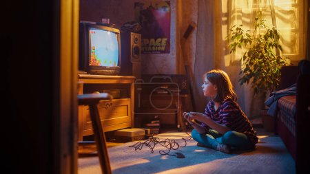 Jeune fille jouant Eighties Eight Bit Arcade jeu vidéo sur une console à la maison dans sa chambre avec l'intérieur de la vieille école. L'enfant gagne avec succès le niveau