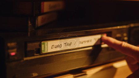 Retro Nineties Technology Concept. Close Up of a Person Inserting a VHS Cassette in a Player with Nostalgic Eurotrip Footage from Home Video Camera