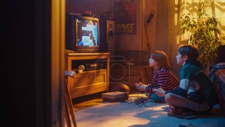 Nostalgic Childhood Concept : Young Brother and Sister jouant au jeu vidéo d'arcade 8 bits en 2D sur un téléviseur rétro installé à la maison dans une pièce avec des règles correctes