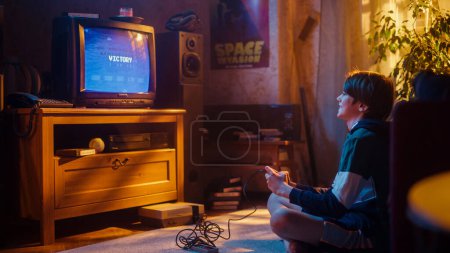 Jeune garçon jouant 80s Eight Bit Arcade Space Shooter jeu vidéo sur une console à la maison dans sa chambre Vintage avec l'intérieur de la vieille école. Enfant avec succès