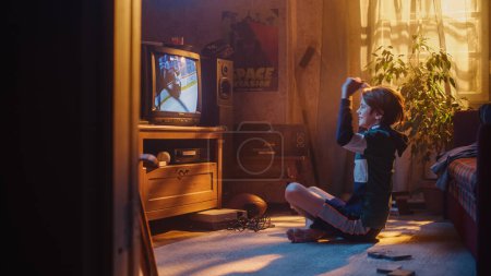 Nostalgic Retro Childhood Concept. Jeune garçon regarde match de hockey à la télévision dans sa chambre avec intérieur daté. Soutenir son équipe préférée et obtenir