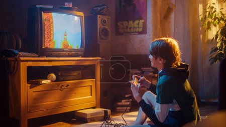 Jeune garçon jouant Eighties Eight Bit Arcade jeu vidéo sur une console à la maison dans sa chambre avec l'intérieur de la vieille école. Enfant gagne avec succès la