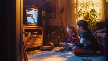 Nostalgique et heureux concept d'enfance : jeune frère et s?ur jouant 8 bits 2D Arcade jeu vidéo sur un téléviseur rétro à la maison dans une chambre avec période