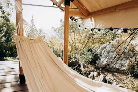 Hängematte für Ruhe und Entspannung auf der Veranda mit Blick auf den Wald und die Berge. Campingausrüstung an der frischen Luft in der Natur und im Gesundheitswesen.
