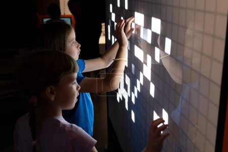 Zwei junge Kinder im Grundschulalter, Mädchen, die gemeinsam eine interaktive Touchscreen-Schnittstelle nutzen, Kinder und moderne Technologie Interaktion, Bildung und Lernen, Lehrmittel abstraktes Konzept