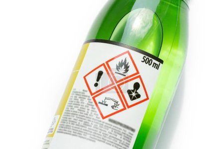 A green bottle of highly corrosive flammable chlorinated rubber nitro solvent with printed on warning symbols label, sticker. Dangerous chemical substances abstract concept, closeup, detail, nobody