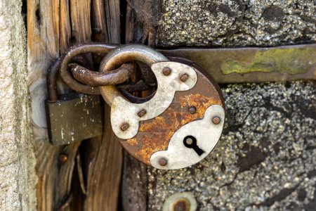 Téléchargez les photos : A large old rusty metal padlock, object detail, closeup, big steel lock up close, keyhole, locked door, safety security symbol, protection abstract concept, closed shed, shack, gate, nobody, no people - en image libre de droit