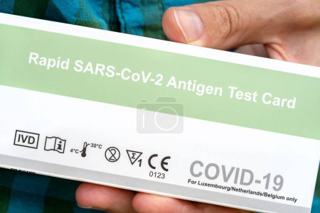 Téléchargez les photos : Rapid SARS-Cov-2 Antigen Test Card COVID-19 coronavirus test package, box held in hand, detail, extreme closeup, man holding an issued covid test in hand, medical supplies - en image libre de droit