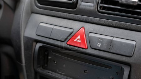 Generisches rotes Dreieck Not-Halt-Warnblinklicht Taste auf dem Armaturenbrett des Autos, Innenraum Objekt Detail Nahaufnahme, niemand. Kfz-Unfälle und Notfälle abstraktes Konzept, alte staubige Gebrauchtwagen im Inneren