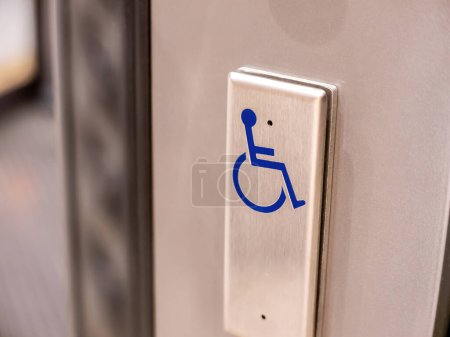 Ein Metallknopf mit einem blauen Rollstuhlsymbol darauf, Objektnahaufnahme, niemand. Barrierefreiheit für Behinderte, architektonisches Design für Menschen mit Behinderungen, einfaches abstraktes Konzept