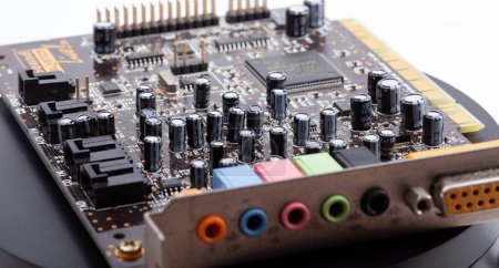 Detailed close-up of an old desktop PC sound card with its electronic components exposed, capacitors resistors, and color-coded audio input output jacks, old PC parts