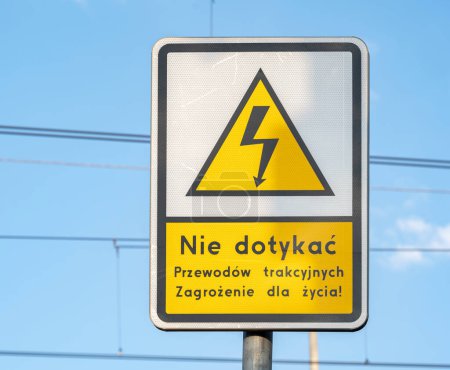 Warnschild mit Warnhinweis auf Polnisch davor, Oberleitungen zu berühren, die auf ein lebensbedrohliches Gefahrenkonzept hinweisen. Universelles elektrisches Schocklicht-Symbol, niemand, Frontansicht