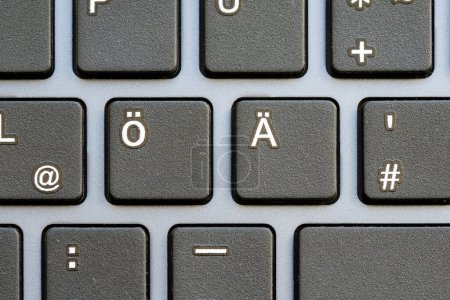 Eine Makroaufnahme, die die Taste mit der Diäerose-Taste auf einer schwarzen Computertastatur zeigt, mit umgebenden Tasten, die weich verschwommen sind, extremen Nahaufnahmen, niemand. Eingabe von Sonderzeichen, Sprachkonzept