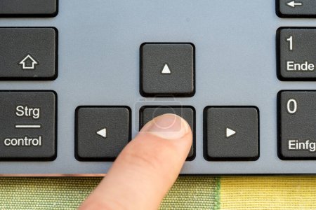 Finger pressing the back arrow key on a computer keyboard, indicating a reverse action or navigation step, going back in reverse backwards movement symbol simple abstract concept, one person, top view