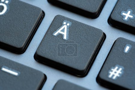 A macro shot showcasing the a with diaeresis key button on a black computer keyboard, with surrounding keys softly blurred, extreme closeup detail, nobody. Special characters input, languages concept