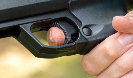 Detallado primer plano de un dedo índice de personas colocado en el gatillo de una pistola negra, hombre anónimo listo para disparar un arma de fuego deporte simple, pistola de aire, disparando un arma. Reglas de seguridad de armas, deportes y armas
