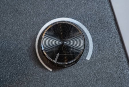 Primer plano detallado de un dial giratorio electrónico gris gris gris plateado texturizado, parte de un mezclador de sonido digital o dispositivo electrónico, dial ajustado a la posición más baja, a cero, mínimo, desactivado